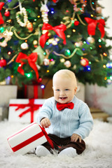 Fototapeta na wymiar Funny baby with gift box and Christmas tree on background