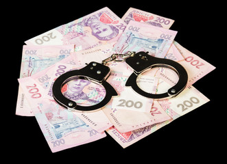 Ukrainian hryvnia with handcuffs close up isolated on a black ba