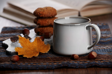 Cup of tea with autumn decor on wooden table.