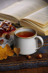 Cup of tea with autumn decor on wooden table.