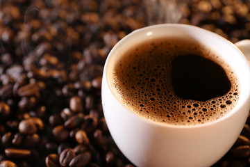 Cup of hot coffee on coffee beans background
