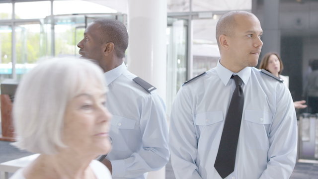  Airport security guards on duty, chatting and watching passengers walk by