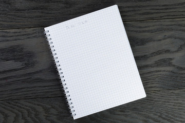 blank notepad with chequered pages on gray wood table with to do list phrase