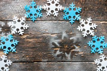 Frame of snowflakes on the artificial snow on a wooden background