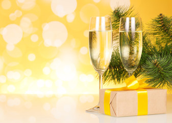 Two glasses with champagne and gift on background