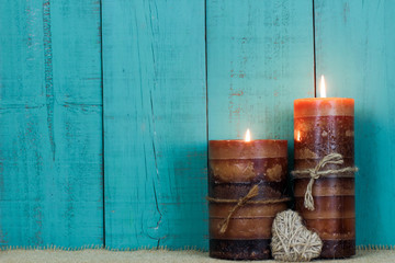 Candles by rope heart and rustic wood background