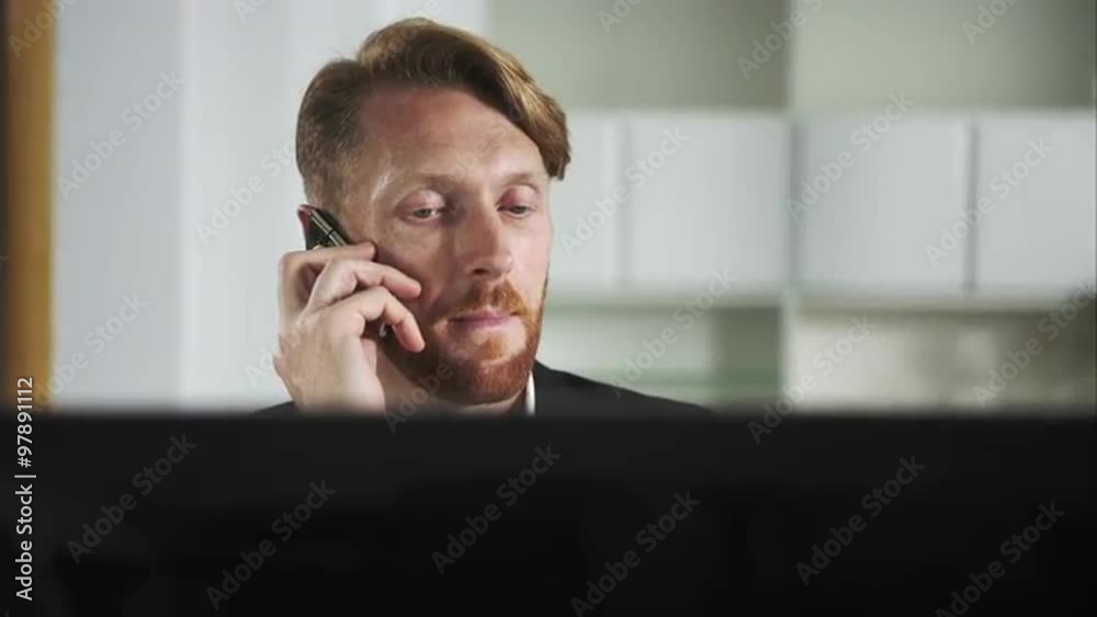 Aufkleber Red-haired man sitting at a computer and calling on the phone