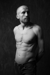 Naklejka premium strong serious athletic young man on dark background looking awa