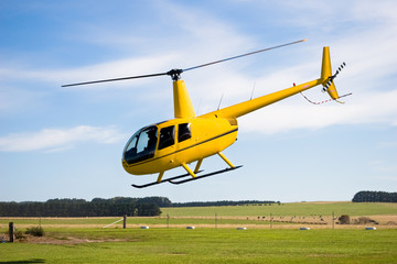 Yellow helicopter taking off in countryside