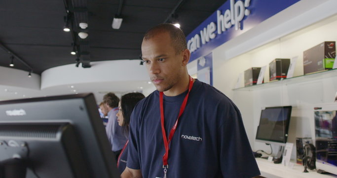 Helpful salesman serving customers in consumer electronics store showroom