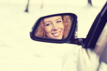 Happy woman driver reflection in car side view mirror. Safe winter trip, journey driving concept