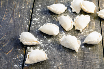 Raw dumplings with potatoes and onions on dark wooden table