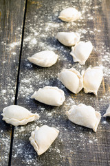 Raw dumplings with potatoes and onions on dark wooden table
