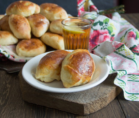 Russian baked patties on wooden cutboard and lemon tea