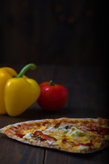 Obraz na płótnie Canvas slice of pizza with vegetables on a wooden background