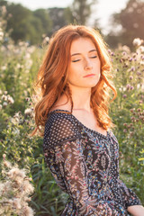 Woman with closed eyes is standing in a meadow