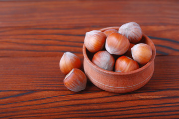 Натуральный свежий фундук в скорлупе в деревянной чаше на деревянном фоне