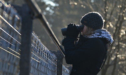 girl looking through binoculars over fence