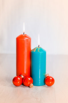 Two candles and three Christmas balls on a wooden surface
