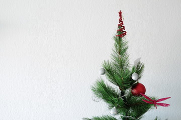 Christmas tree with ornaments on white wall background with space for text
