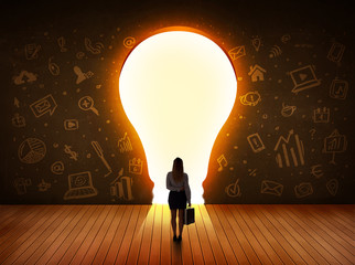 Business woman looking at bright light bulb in the wall