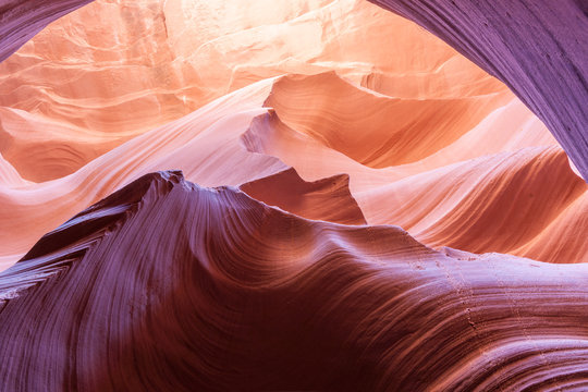 Magnificent nature sun filters into Lower Antelope Canyon Page Arizona USA while the shapes and swirls create and abstract nature image and silica in sandstone reflects some intense colors.