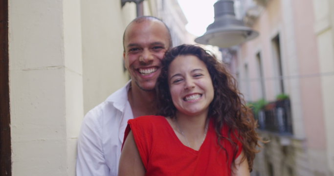  Portrait of romantic couple on hotel or apartment balcony, blowing kisses to camera. 