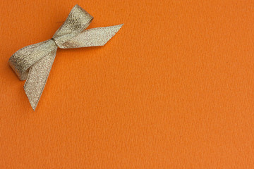 Golden bow on orange background