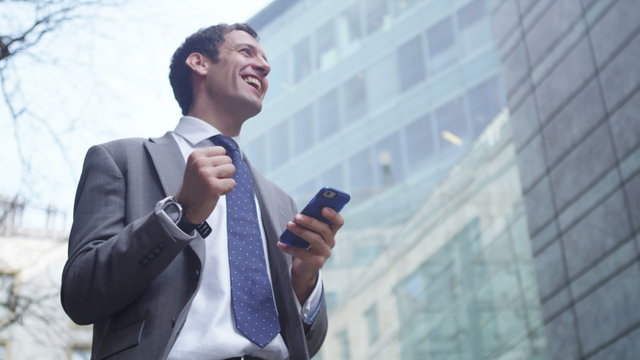   businessman celebrating news of deal as he checks his smartphone.