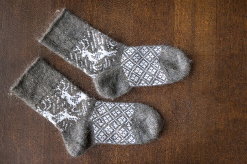 Warm knitted socks with nordic ornament on wooden table