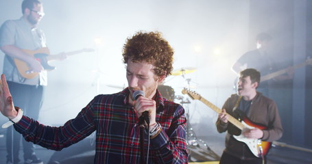  Attractive charismatic male singer performing with band at live music event