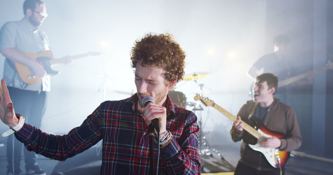  Attractive charismatic male singer performing with band at live music event