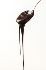 Dark chocolate sauce into spoon on white background