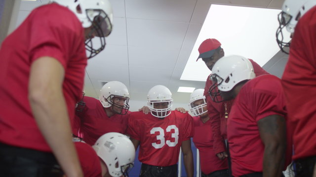  American football coach in locker room, psyching up players before the game