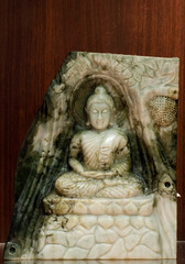 Jade sculpture of buddha isolated on wooden background