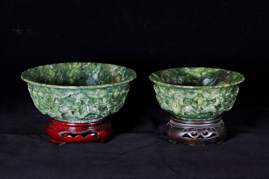 Two Jade bowls with wooden base isolated on dark background