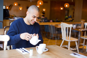 young man enjoying a cup of tea in a cafeteria.