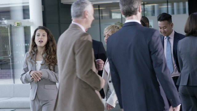  Large diverse business group talking as they walk through office building