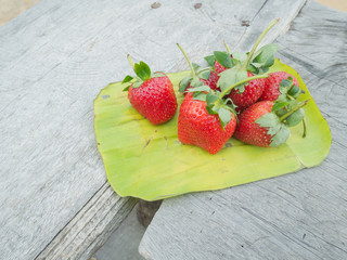 strawberries in a banana leaf on the wooden table