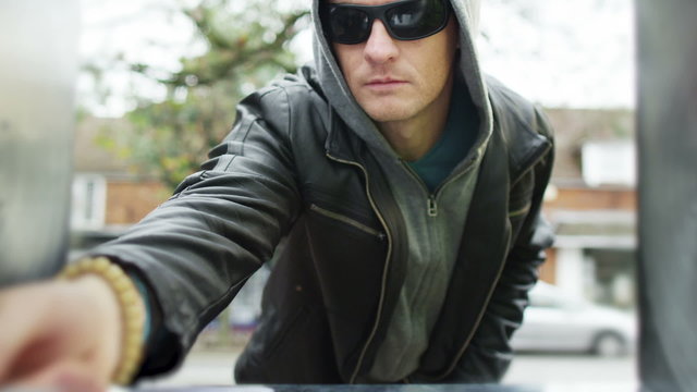 Suspicious character takes money from an ATM machine with a stolen card