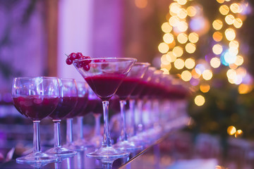 Beautiful row line of different colored alcohol cocktails with mint on a christmas party, martini, vodka with bubbles, wine and others on decorated catering bouquet table on open air event, picture 
