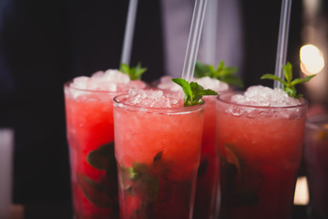 Beautiful row line of different colored alcohol cocktails with mint on a christmas party, martini, vodka with bubbles, wine and others on decorated catering bouquet table on open air event, picture 