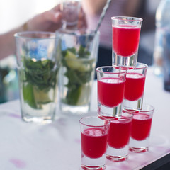 Beautiful row line of different colored alcohol cocktails with mint on a christmas party, martini, vodka with bubbles, wine and others on decorated catering bouquet table on open air event, picture 