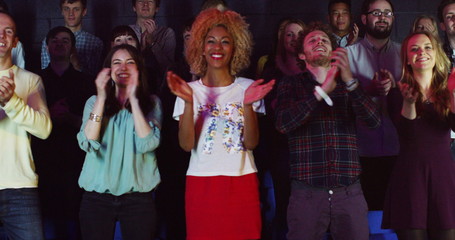  Young theatre audience give a standing ovation to the performers on stage