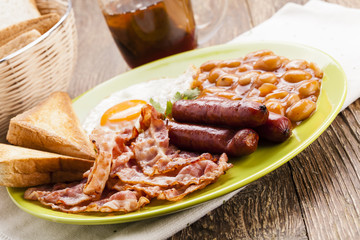 Full english breakfast with bacon, sausage, fried egg, baked bea
