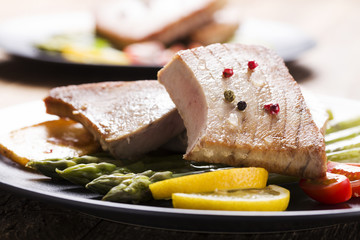 Grilled tuna steak served on asparagus with roasted potatoes.