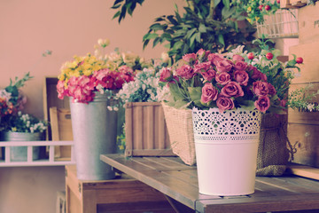 Beautiful flowers in vase on wooden table with vintage filter blur background