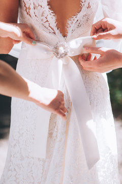bridesmaid buttoning the dress on bride, details of beautiful la
