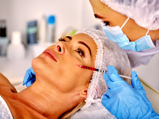 Fototapeta premium Woman middle-aged in spa salon with beautician. Female giving botox injections