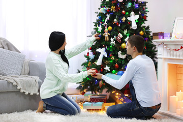 Happy couple on the floor with gifts in the decorated Christmas room